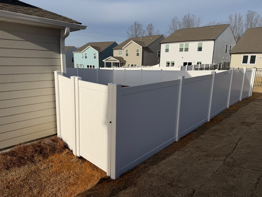 Vinyl privacy fence panels installed along a property line